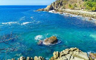 Surfer waves turquoise blue water rocks cliffs boulders Puerto Escondido. photo