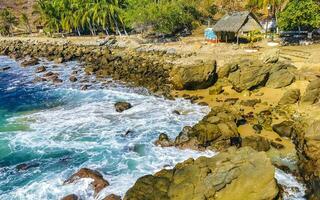 Surfer waves turquoise blue water rocks cliffs boulders Puerto Escondido. photo