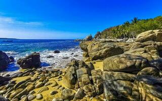 Surfer waves turquoise blue water rocks cliffs boulders Puerto Escondido. photo