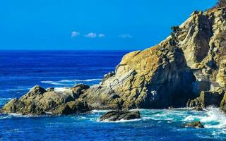 Surfer waves turquoise blue water rocks cliffs boulders Puerto Escondido. photo