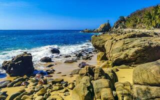 Surfer waves turquoise blue water rocks cliffs boulders Puerto Escondido. photo