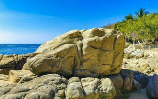 Surfer waves turquoise blue water rocks cliffs boulders Puerto Escondido. photo