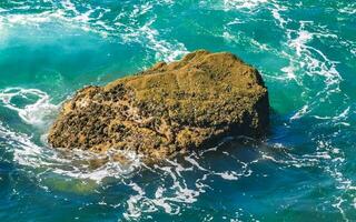 Surfer waves turquoise blue water rocks cliffs boulders Puerto Escondido. photo