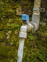 Running water faucet against old brick wall background photo