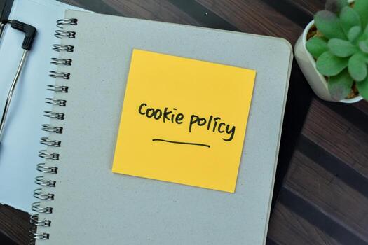 Concept of Cookie Policy write on sticky notes isolated on Wooden Table. photo