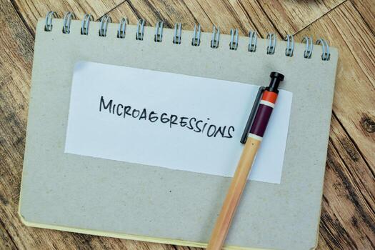 Concept of Microaggressions write on sticky notes isolated on Wooden Table. photo