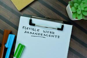 Concept of Flexible work Arrangements write on paperwork isolated on Wooden Table. photo