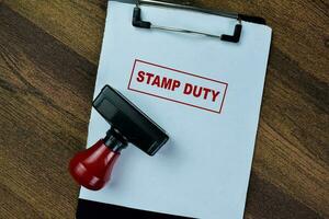 Concept of Red Handle Rubber Stamper and Stamp Duty text isolated on on Wooden Table. photo