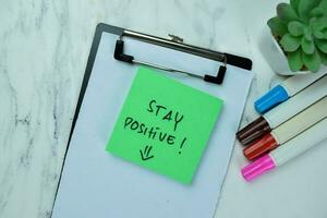 Concept of Stay Positive write on sticky notes isolated on Wooden Table. photo