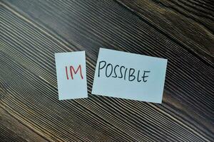 Concept of Impossible to be possible write on sticky notes isolated on Wooden Table. photo