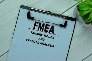 Concept of FMEA - Failure Modes and Effects Analysis write on paperwork isolated on Wooden Table. photo