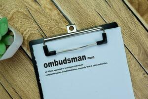 Concept of Definition Ombudsman word write on paperwork isolated on Wooden Table. photo