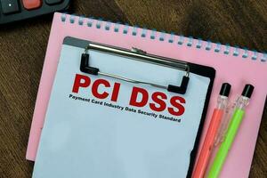 Concept of PCI DSS - Payment Card Industry Data Security Standard write on paperwork isolated on Wooden Table. photo
