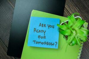Concept of Are You Ready For Tomorrow write on sticky notes isolated on Wooden Table. photo
