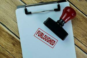 Concept of Red Handle Rubber Stamper and Furloughed text isolated on on Wooden Table. photo