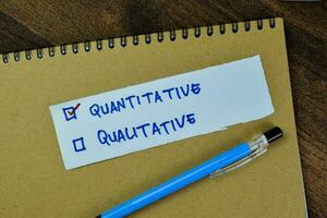 Concept of Quantitative and Qualitative write on sticky notes isolated on Wooden Table. photo