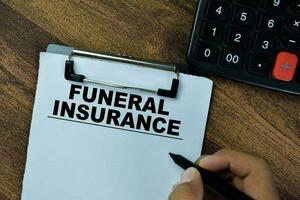 Concept of Funeral Insurance write on paperwork on a book isolated on Wooden Table. photo