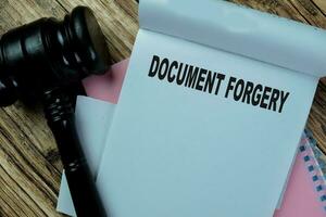 Concept of Document Forgery write on book with gavel isolated on Wooden Table. photo