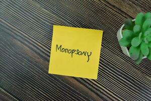 Concept of Monopsony write on sticky notes isolated on Wooden Table. photo