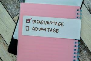 Concept of Disadvantage write on sticky notes isolated on Wooden Table. photo