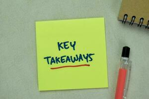 Concept of Key Takeaways write on sticky notes isolated on Wooden Table. photo