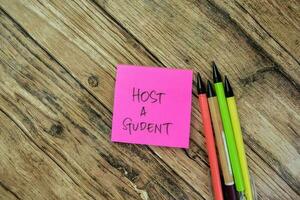 Concept of Host a Student write on sticky notes isolated on Wooden Table. photo