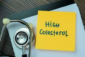 Concept of High Cholesterol write on sticky notes isolated on Wooden Table. photo