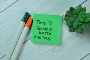Concept of Time is Precious Waste It Wisely write on sticky notes isolated on Wooden Table. photo