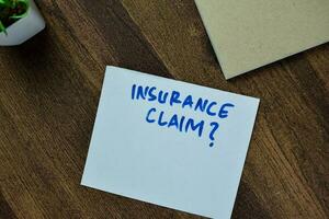 Concept of Insurance Claim write on sticky notes isolated on Wooden Table. photo