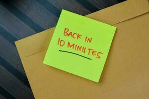 Concept of Back in 10 Minutes write on sticky notes isolated on Wooden Table. photo