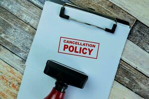 Concept of Red Handle Rubber Stamper and Cancellation Policy text isolated on on Wooden Table. photo