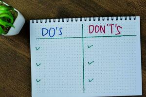 Concept of Do's and Don't's write on book isolated on Wooden Table. photo