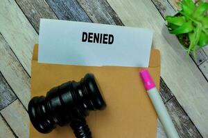 Concept of Gavel and Denied text above brown envelope isolated on on Wooden Table. photo