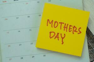Concept of Mothers Day write on sticky notes with calendar isolated on Wooden Table. photo
