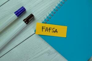 Concept of FAFSA write on sticky notes isolated on Wooden Table. photo