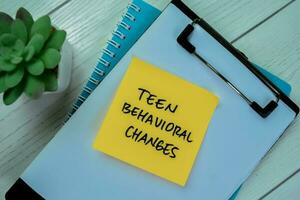 Concept of Teen Behavioral Changes write on sticky notes isolated on Wooden Table. photo