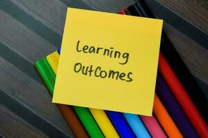 Concept of Learning Outcomes write on sticky notes isolated on Wooden Table. photo