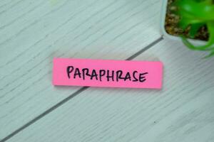 Concept of Paraphrase write on sticky notes isolated on Wooden Table. photo