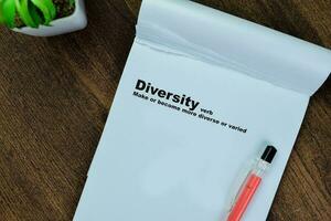 Concept of definition Diversity verb write on book isolated on Wooden Table. photo