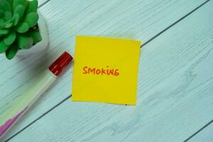 Concept of Smoking write on sticky notes isolated on Wooden Table. photo