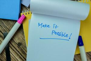 Concept of Make it Possible write on book isolated on Wooden Table. photo