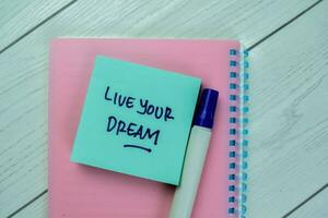 Concept of Live Your Dream write on sticky notes isolated on Wooden Table. photo