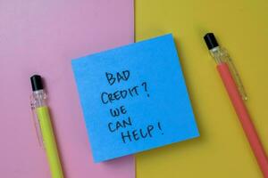 Concept of Bad Credit We Can Help write on sticky notes isolated on Wooden Table. photo