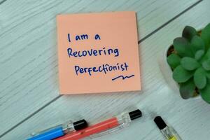 Concept of I am a Recovering Prefectionist write on sticky notes isolated on Wooden Table. photo