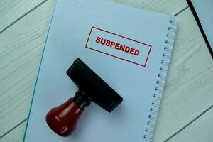 Concept of Red Handle Rubber Stamper and Suspended text isolated on on Wooden Table. photo