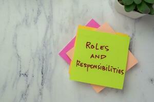 Concept of Roles and Responsibilities write on sticky notes isolated on Wooden Table. photo