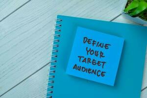 Concept of Define Your Target Audience write on sticky notes isolated on Wooden Table. photo