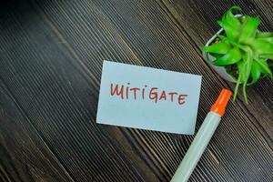 Concept of Mitigate write on sticky notes isolated on Wooden Table. photo
