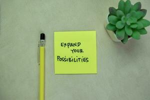Concept of Expand Your Possibilities write on sticky notes isolated on Wooden Table. photo