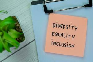 Concept of Diversity, Equality, Inclusion write on sticky notes isolated on Wooden Table. photo